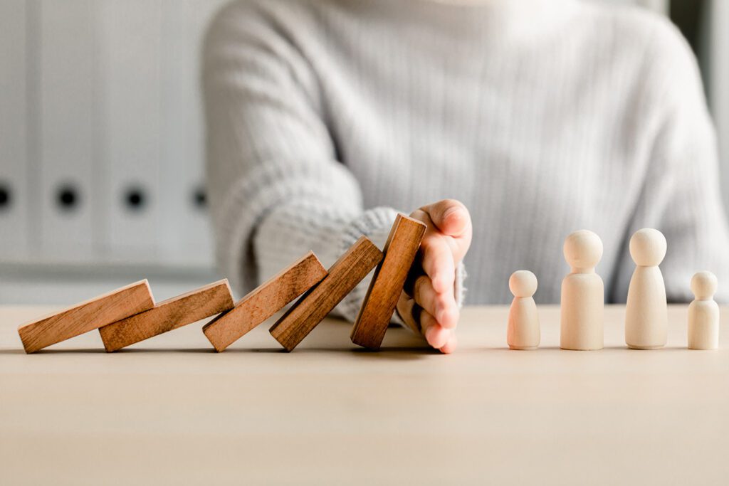 Am image of a person stopping wood dominoes from falling on a family business.